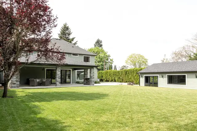Back of a remodeled Clark County area home with a covered stone patio and lawn, by JDI Construction