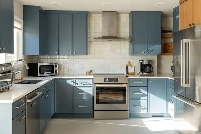 Kitchen with blue-gray shaker cabinets, a square tile backsplash, a stainless range hood and brass pulls