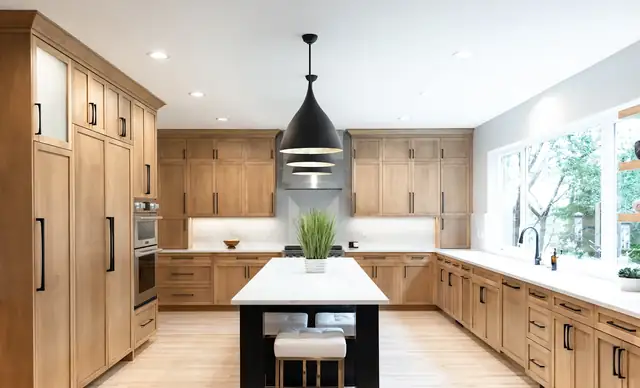 Warm wood kitchen remodel with natural wood shaker cabinets, black-base island with white top and black cone pendant