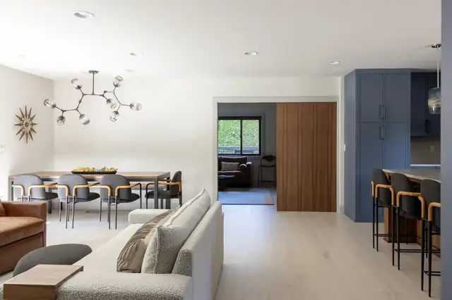 Open living, dining and kitchen area with blue cabinetry and light wood floors from a JDI whole-house remodel